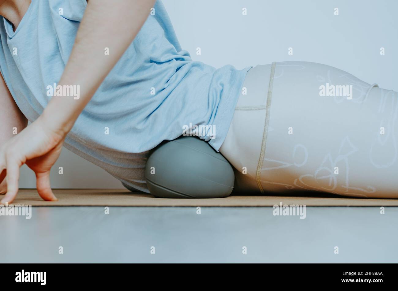 Woman doing visceral self myofascial release on soft grey ball. Concept: self care practices at home, SFMR, MyoYin Stock Photo