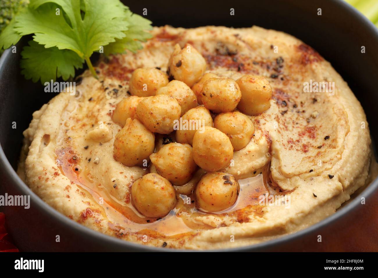 Closeup photo of tasty chickpeas hummus in black plate with smoked paprika Stock Photo