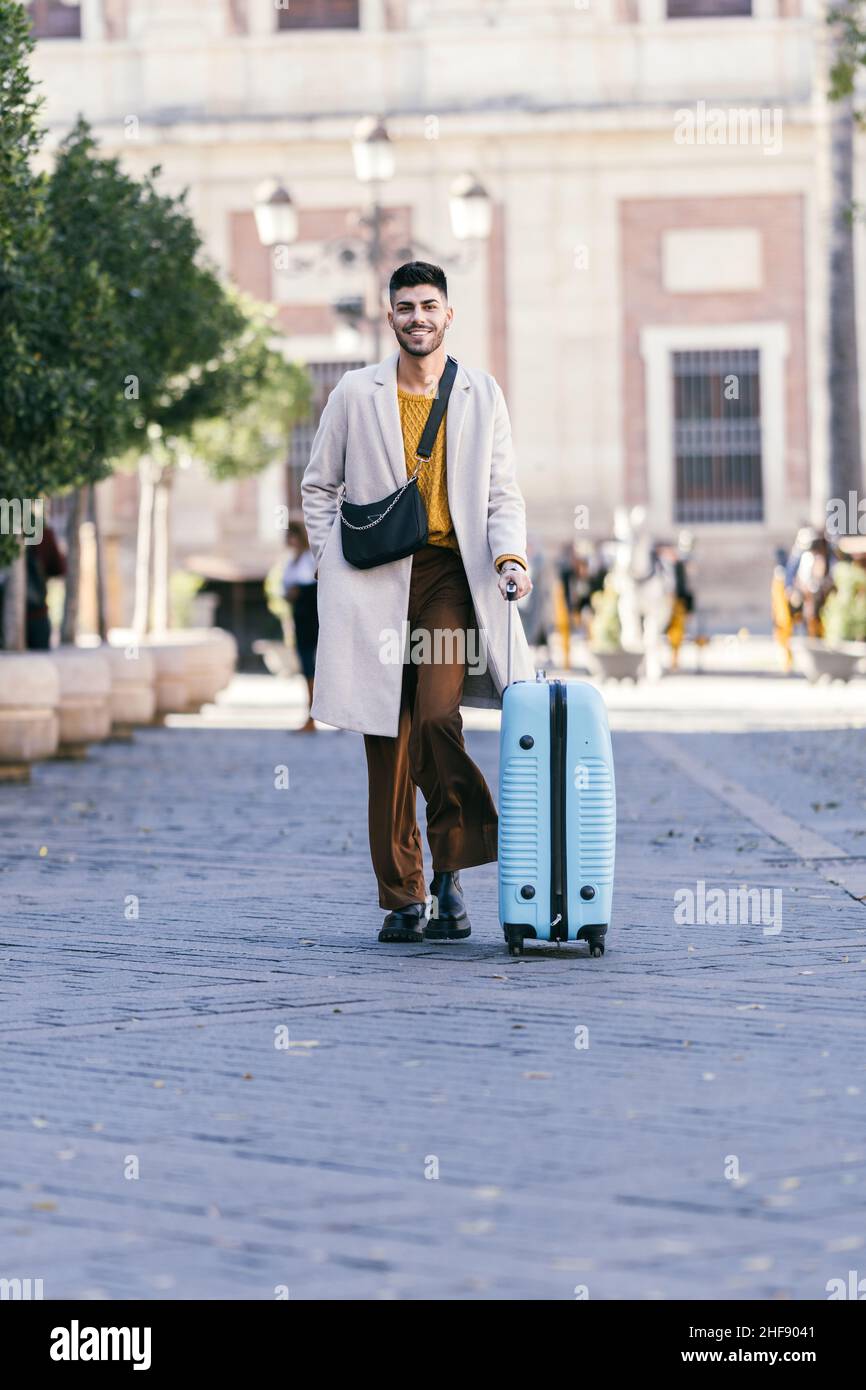 Man with coat carrying a suitcase on the street Stock Photo
