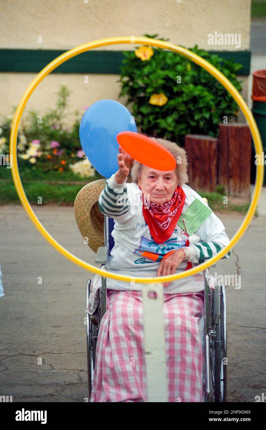 An elderly wheelchairbound woman concentrates as she throws a frisbee