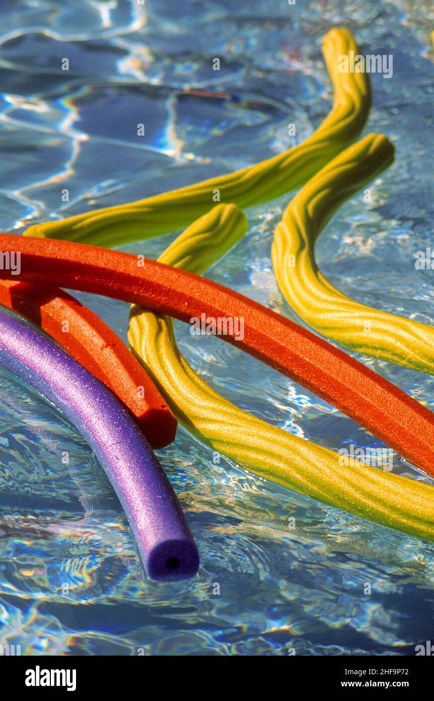 Colorful foam rubber 'Wacky Noodle' floats decorate a swimming pool in afternoon sun. Stock Photo
