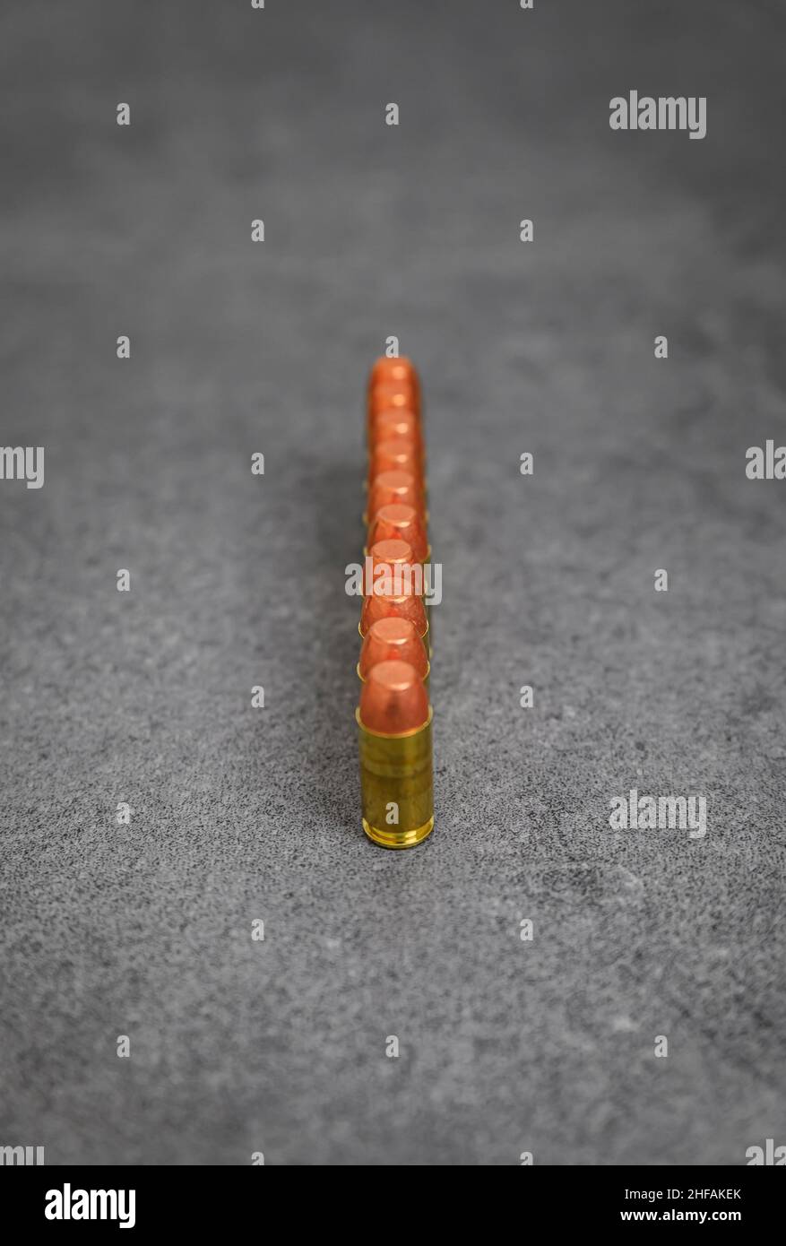 45 ACP caliber full metal jacket bullets unfired rounds lined up on a stone surface Stock Photo