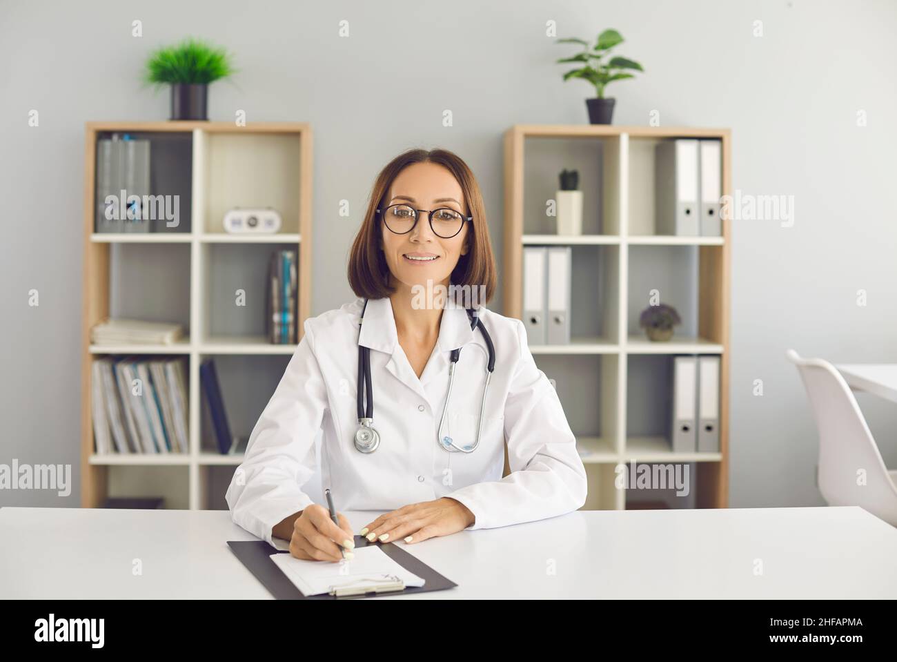 Doctor taking notes during video conference with colleagues or listening to online medical training. Stock Photo