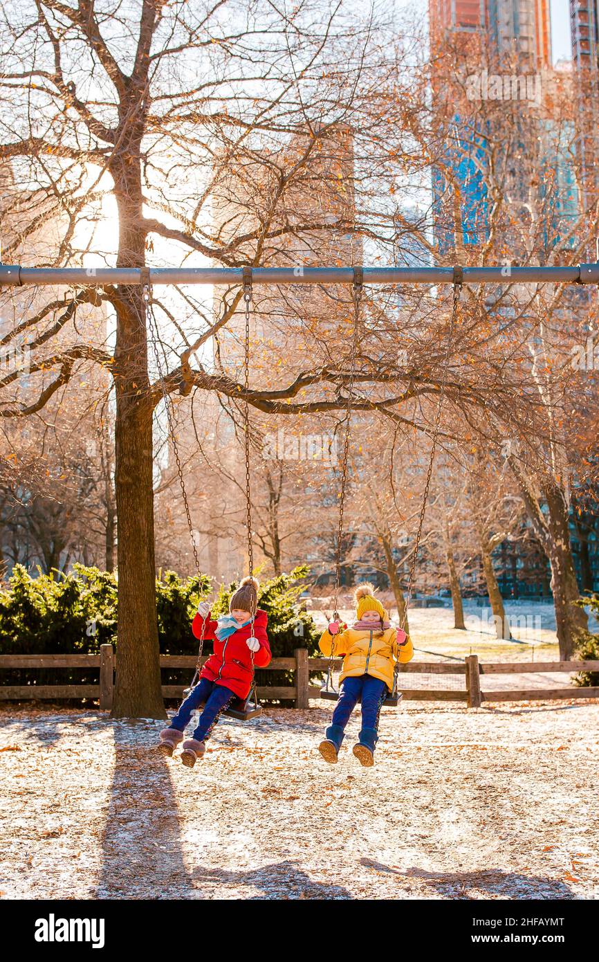 Adorable little girls having fun on the swing in Central Park at New