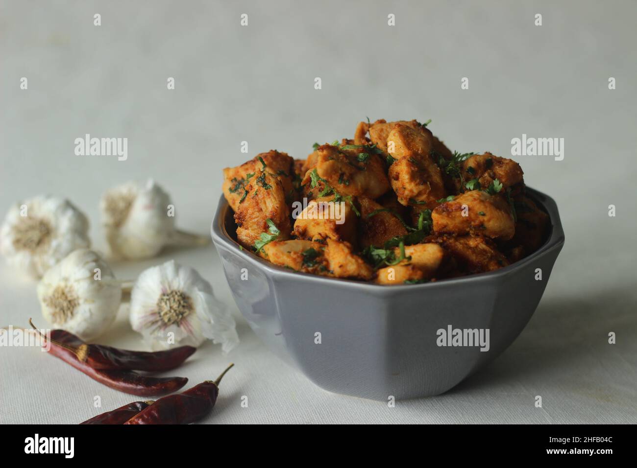 Chilli garlic chicken bites. A pan fried chicken dish with a strong garlic flavour and garnished with fresh coriander leaves. Marinated with garlic pa Stock Photo