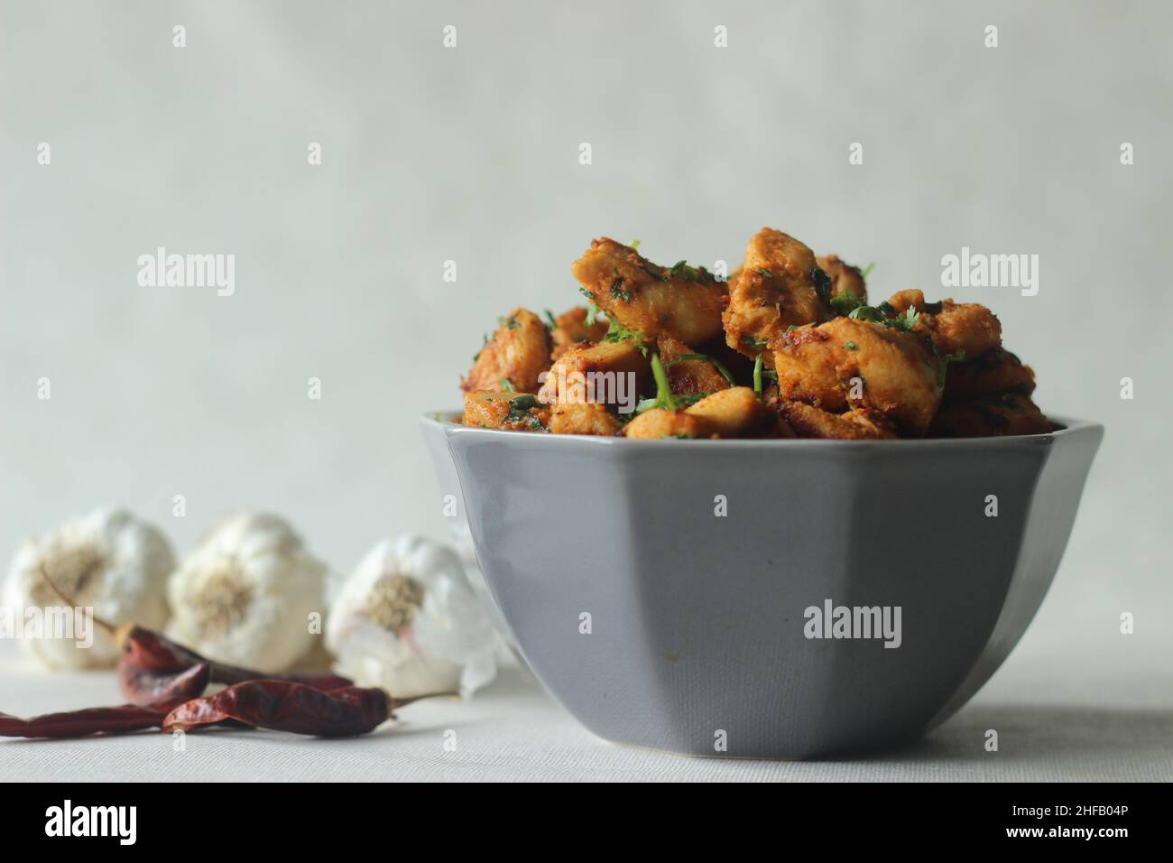 Chilli garlic chicken bites. A pan fried chicken dish with a strong garlic flavour and garnished with fresh coriander leaves. Marinated with garlic pa Stock Photo
