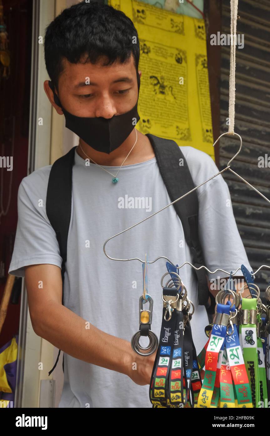 Mandi, Himachal Pradesh, India - 08 02 2021: A asian guy choosing tibetan souvenir in tibetan shop with wearing face mask during coronavirus pandemic Stock Photo