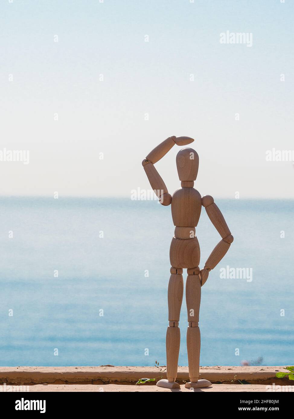 Human wooden doll looking to the horizon of the sea Stock Photo