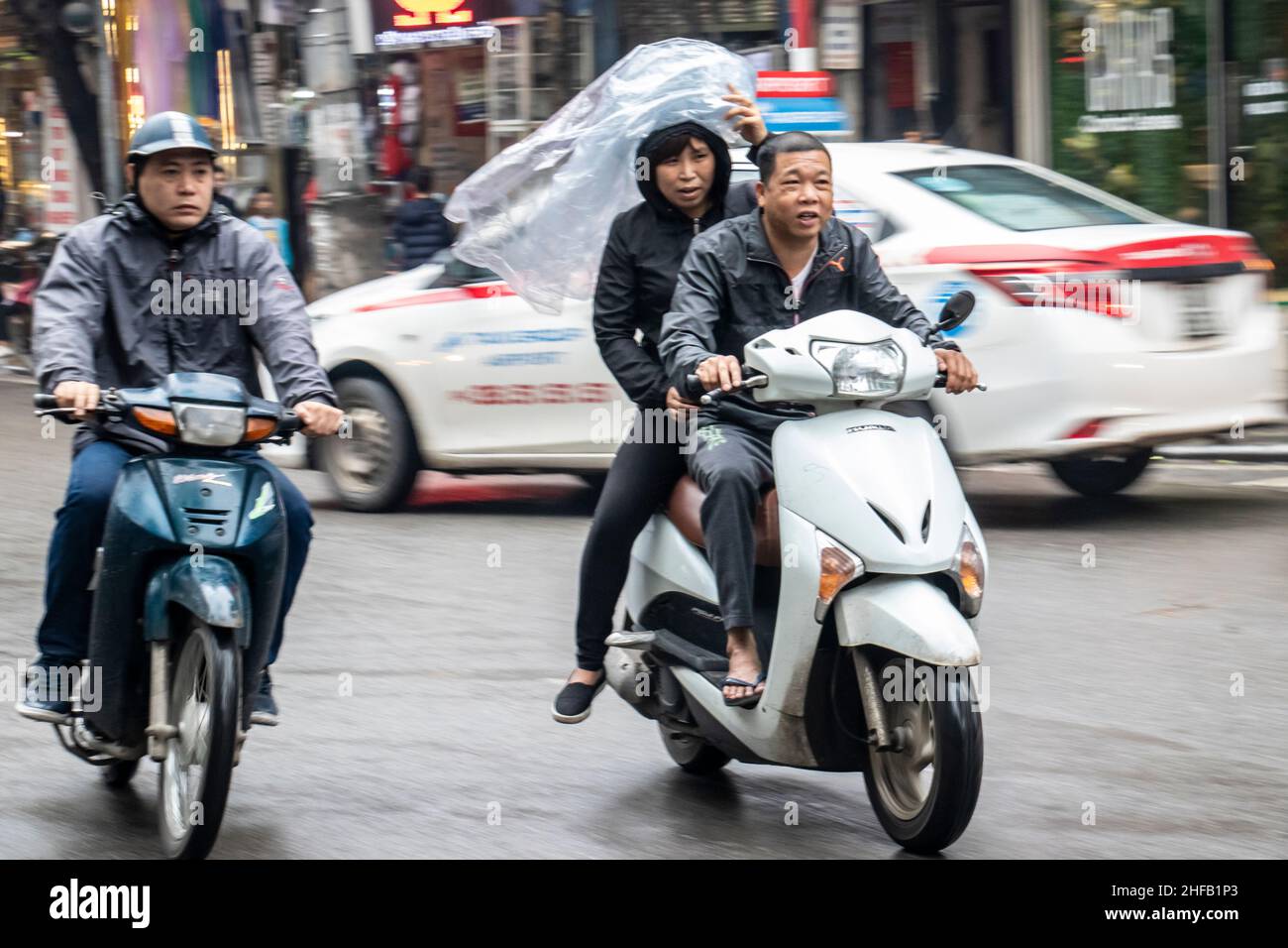 Motorcyclist and cyclist on a wet day in Hanoi Vietnam Stock Photo
