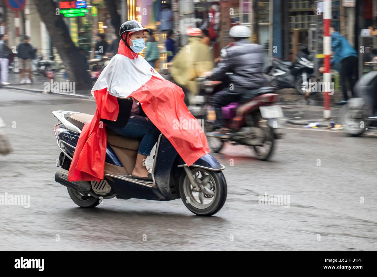 Motorcyclist and cyclist on a wet day in Hanoi Vietnam Stock Photo