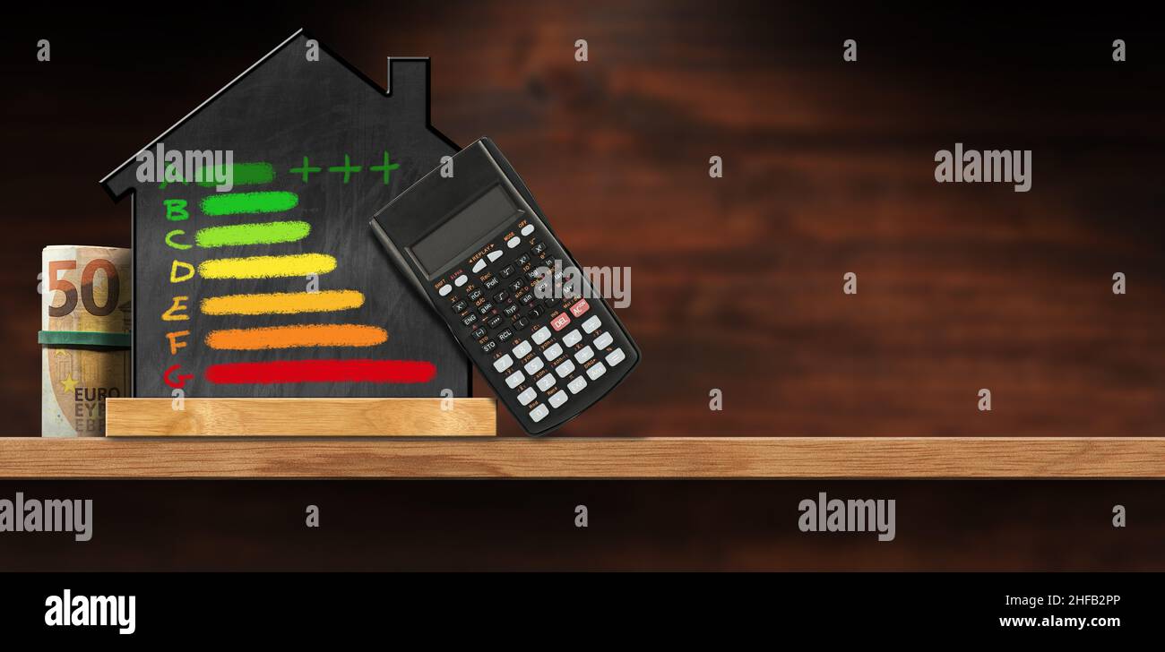 Blackboard in the shape of a house with a chalk drawing of an energy efficiency rating, black calculator and a roll of Euro banknotes, on a table. Stock Photo