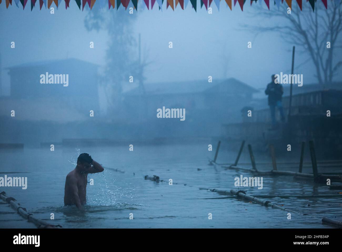 Bhaktapur, Bagmati, Nepal. 15th Jan, 2022. Hindu devotes bathed into the frigid waters during the Makar Mela festival in Panauti, Nepal amid a COVID-19 surge.Makar Mela celebrated once for a month in Magh in interval of 12 years has started on the embankments of trijunction of Punayamata, Roshi and Rudrawati River. The fair begins as the sun enters Makar Rashi on the day of Makar Sakranti, as per the Vedic astrology. After taking bath at the Triveni, the devotees worship Basuki Naag and carry water at the snuff box of the hand and climb up the Gorakhnath Hill to offer water from Triveni. (C Stock Photo
