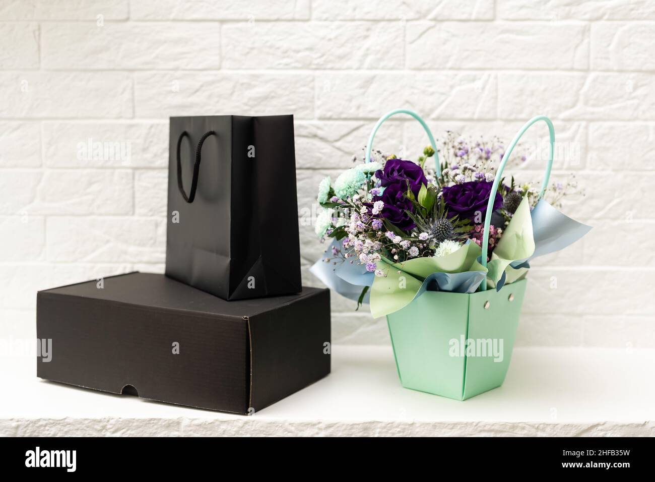 black empty paper bags and bouquets. Blank wall Stock Photo