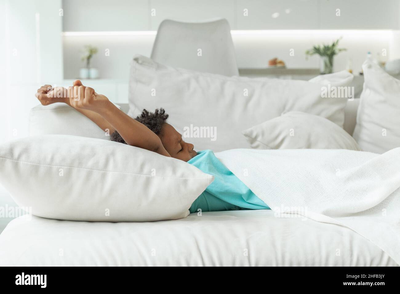Kid in bedroom on bed with white sheet, blanket and pillow. Good