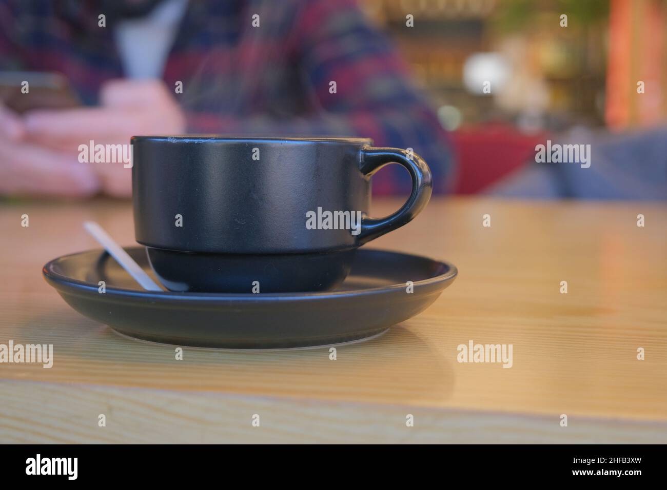 Photo in cafe, coffee in black glass, americano coffee and a blurred man behind of glass and table and smoke. Stock Photo