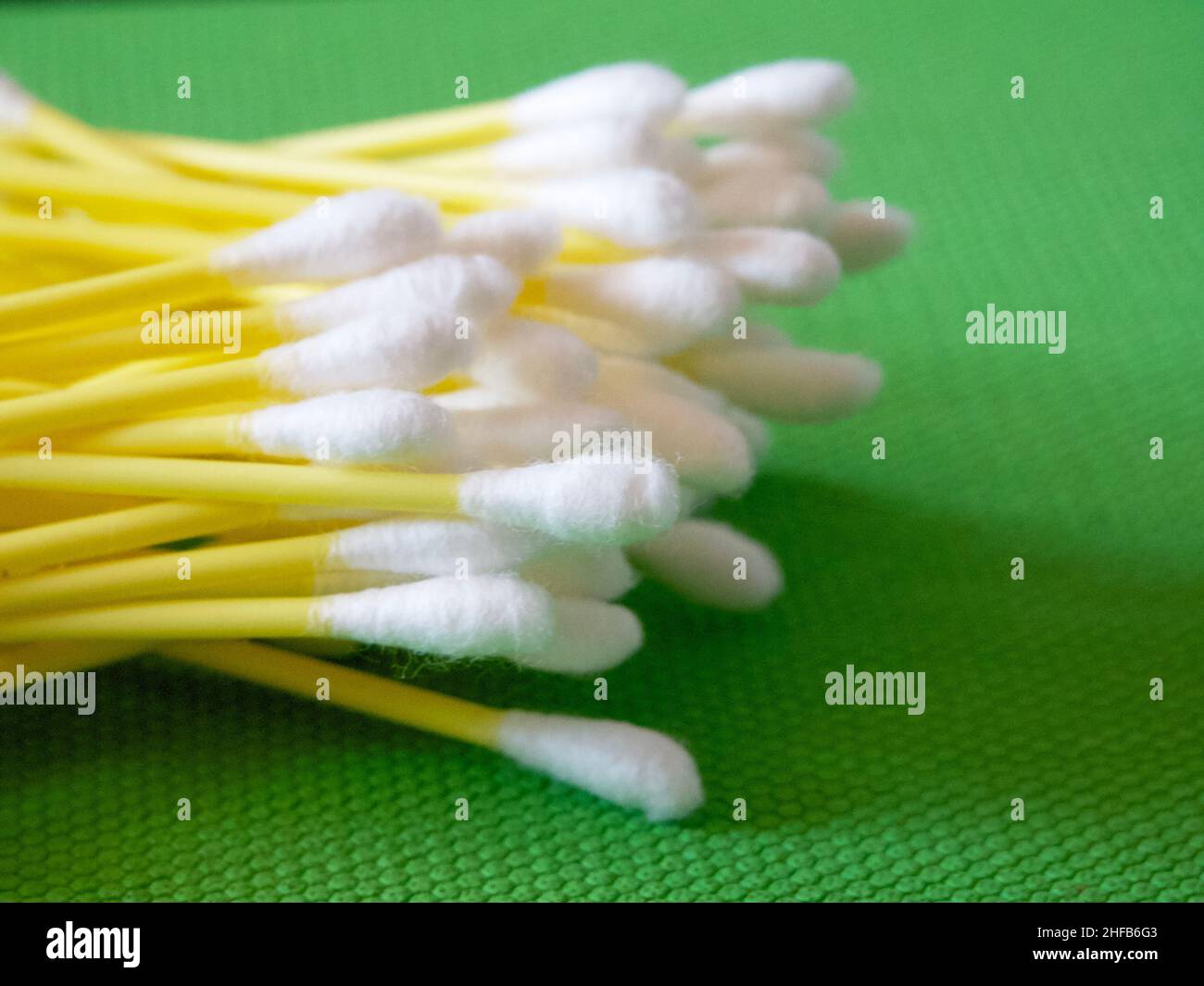A large number of cotton swabs on a green background, a closeup shot
