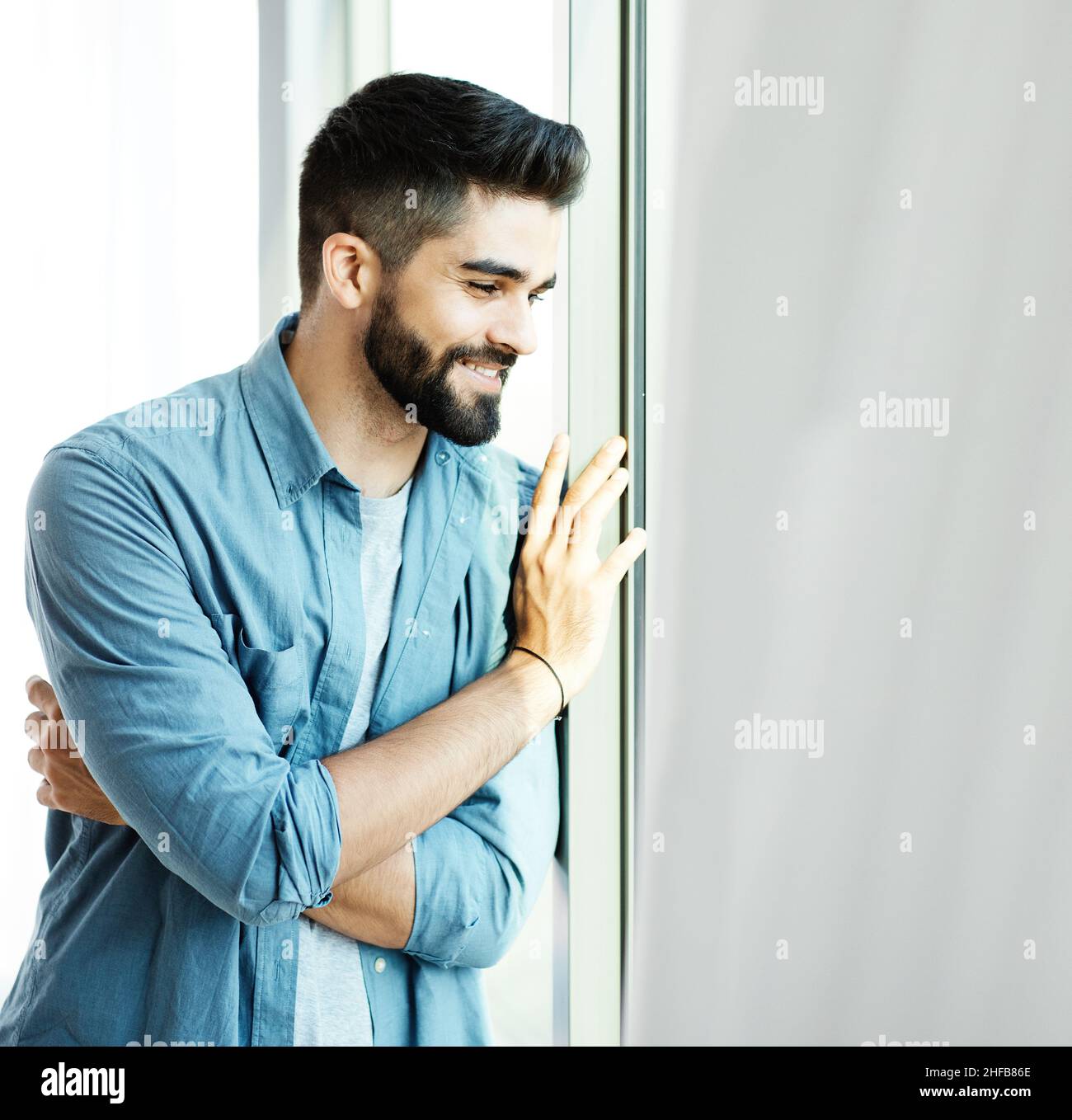 Full Length Portrait Of Stylish Young Fashion Model Man In Bright Red  Sunglasses And Denim Casual Style Posing Near Metallic Door. Standing And  Lean On Grey Wall And Looking Away. Indoor, Studio