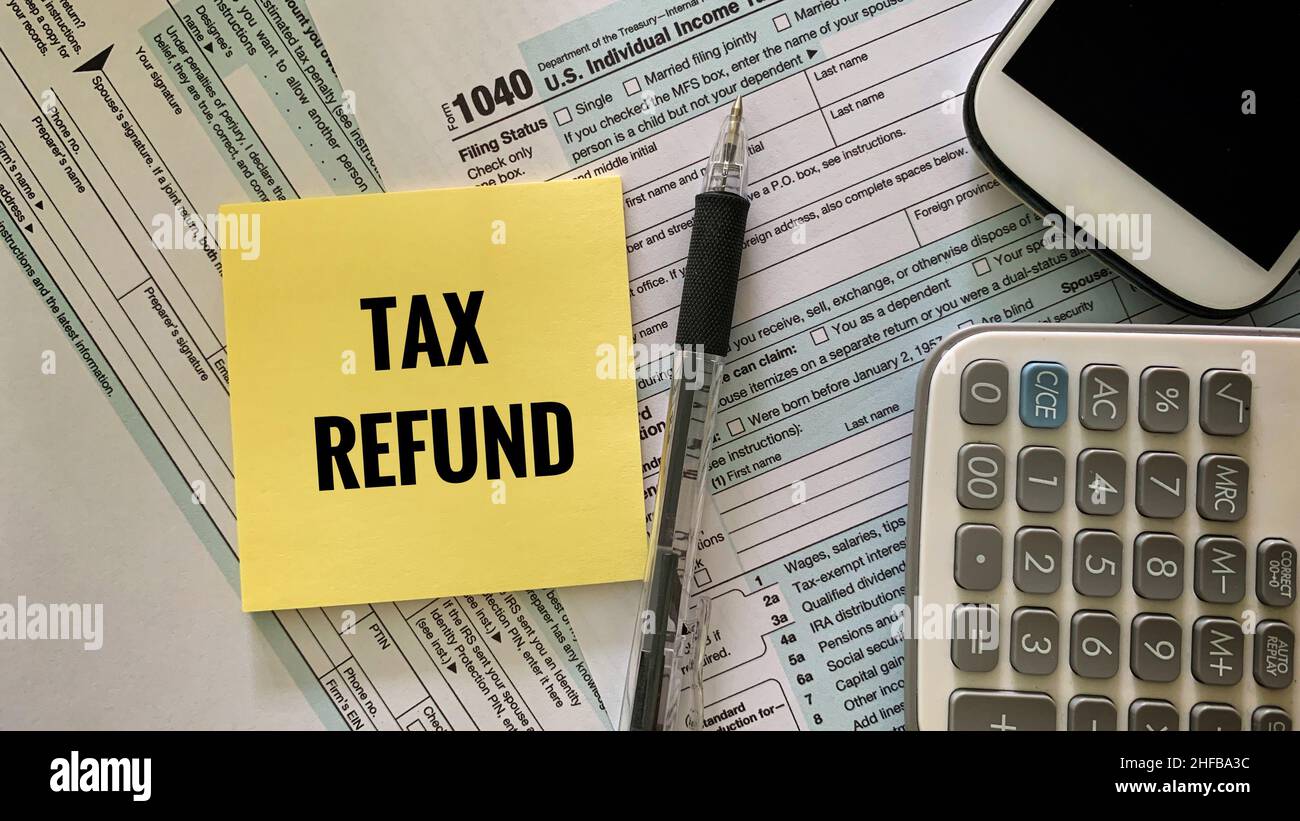 tax refund text on sticky note with 1040 tax form, pen and calculator and mobile phone background. Tax concept. Stock Photo