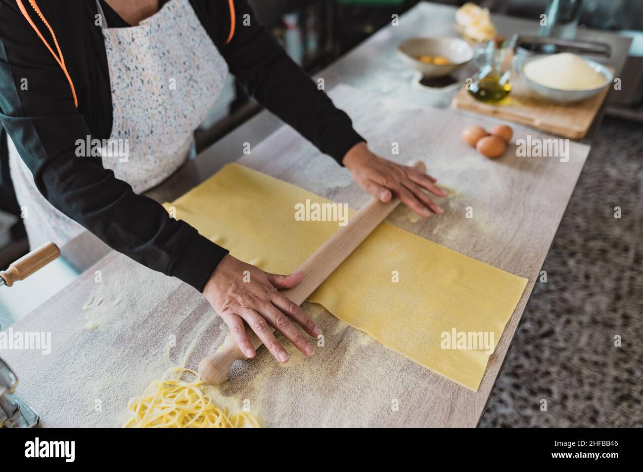 Close up female hands roll the dough preparing fresh homemade pasta Stock Photo