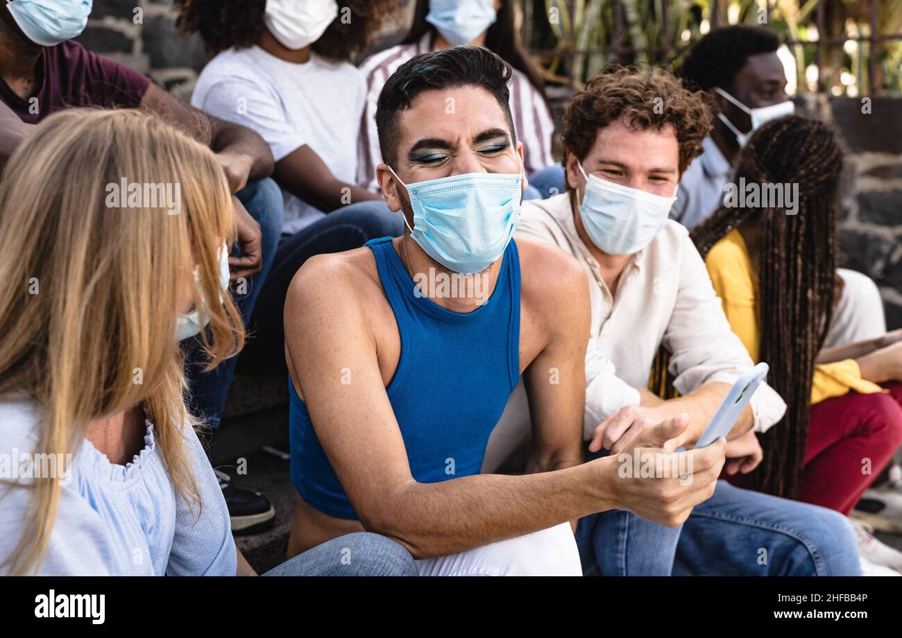 Young multiracial group of friends sitting on urban stairs wearing surgical mask - Youth millennial lifestyle concept Stock Photo