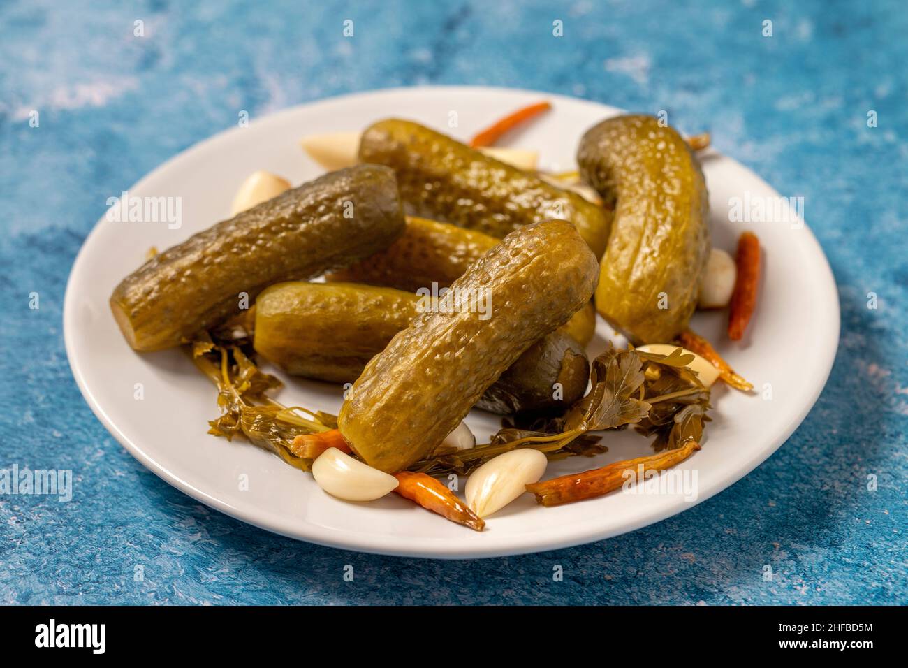 Pickled cucumbers on a blue background. Close-up of pickled cucumbers in a ceramic plate. close up Stock Photo