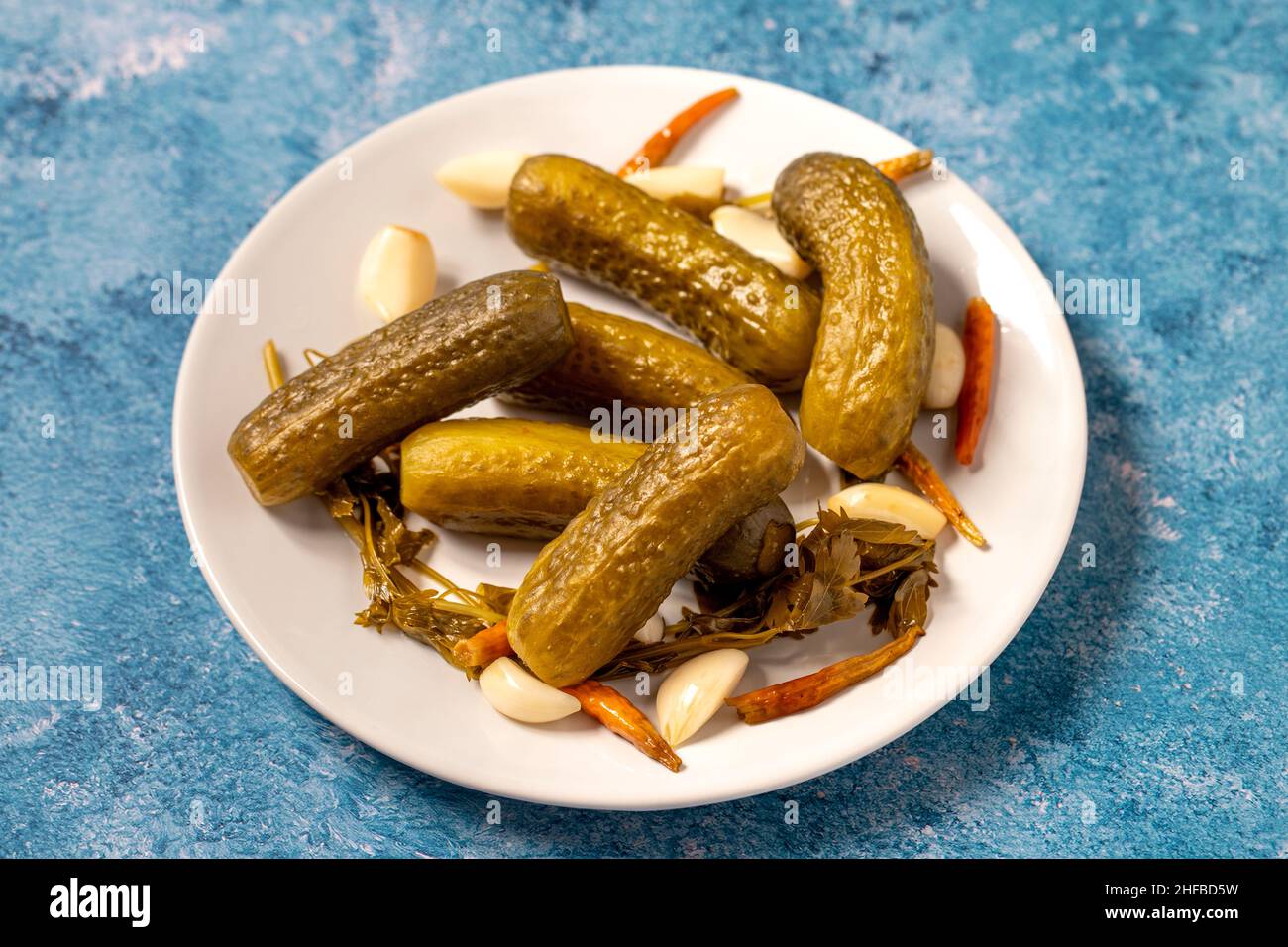 Pickled cucumbers on a blue background. Close-up of pickled cucumbers in a ceramic plate. close up Stock Photo