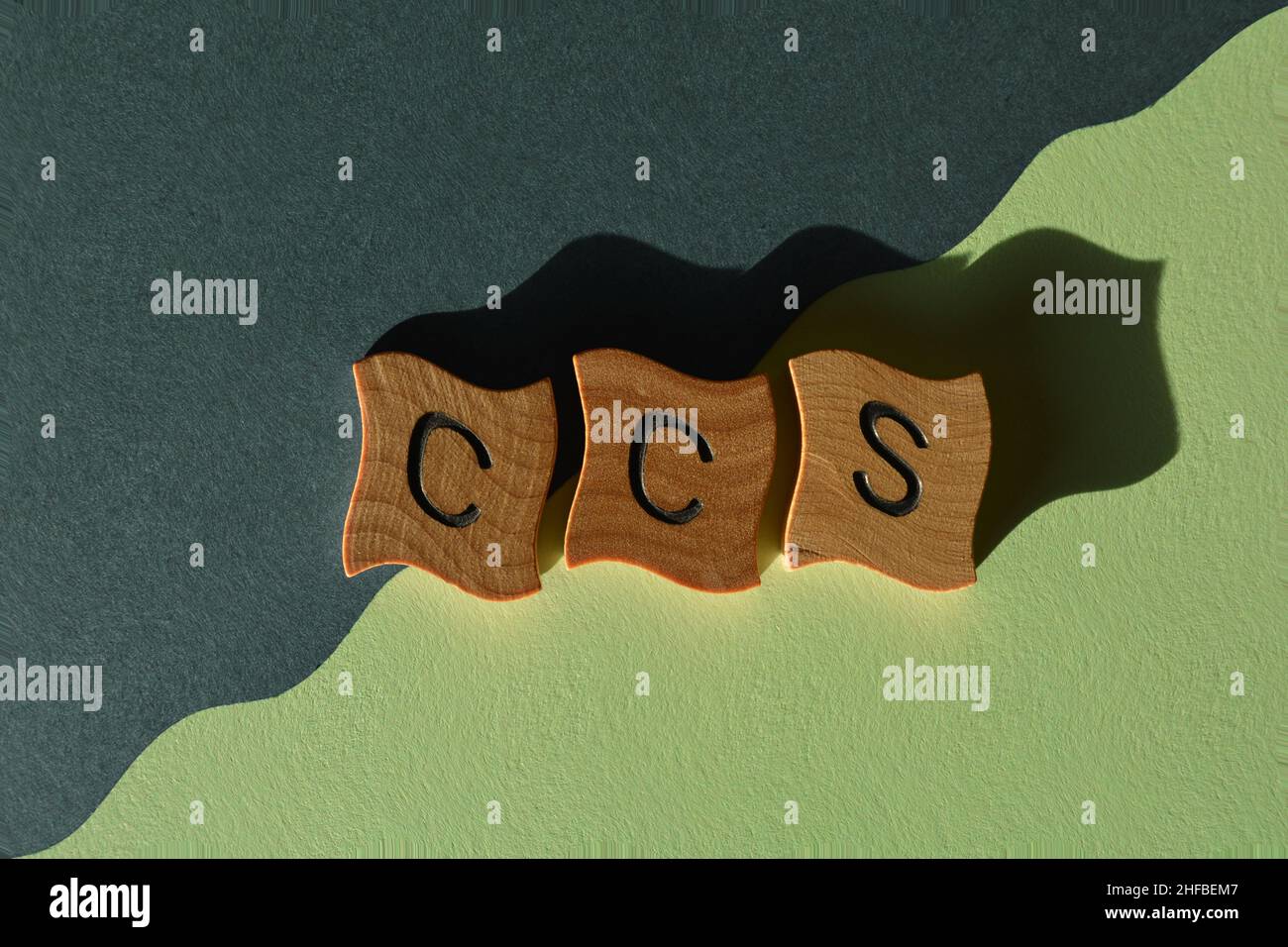 CCS, acronym for Carbon Capture Storage, in wooden alphabet letters isolated on blue and green background Stock Photo