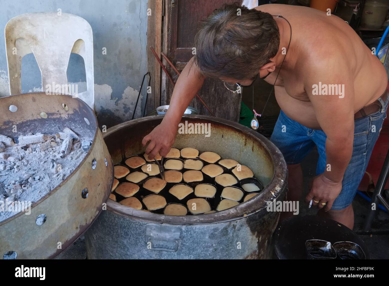 A man in Talat Phlu (market) in Thonburi, Bangkok, Thailand, is making Khanom Khai, a cake-like snack or dessert made from eggs, sugar and flour Stock Photo