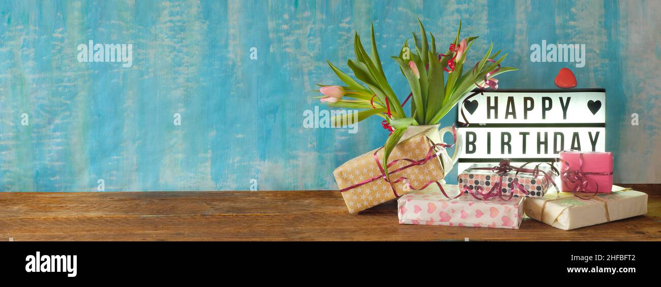 heap of birthday presents and display with caption happy birthday,personal gift and bunch of flowers,personal holiday concept, free copy space, panora Stock Photo