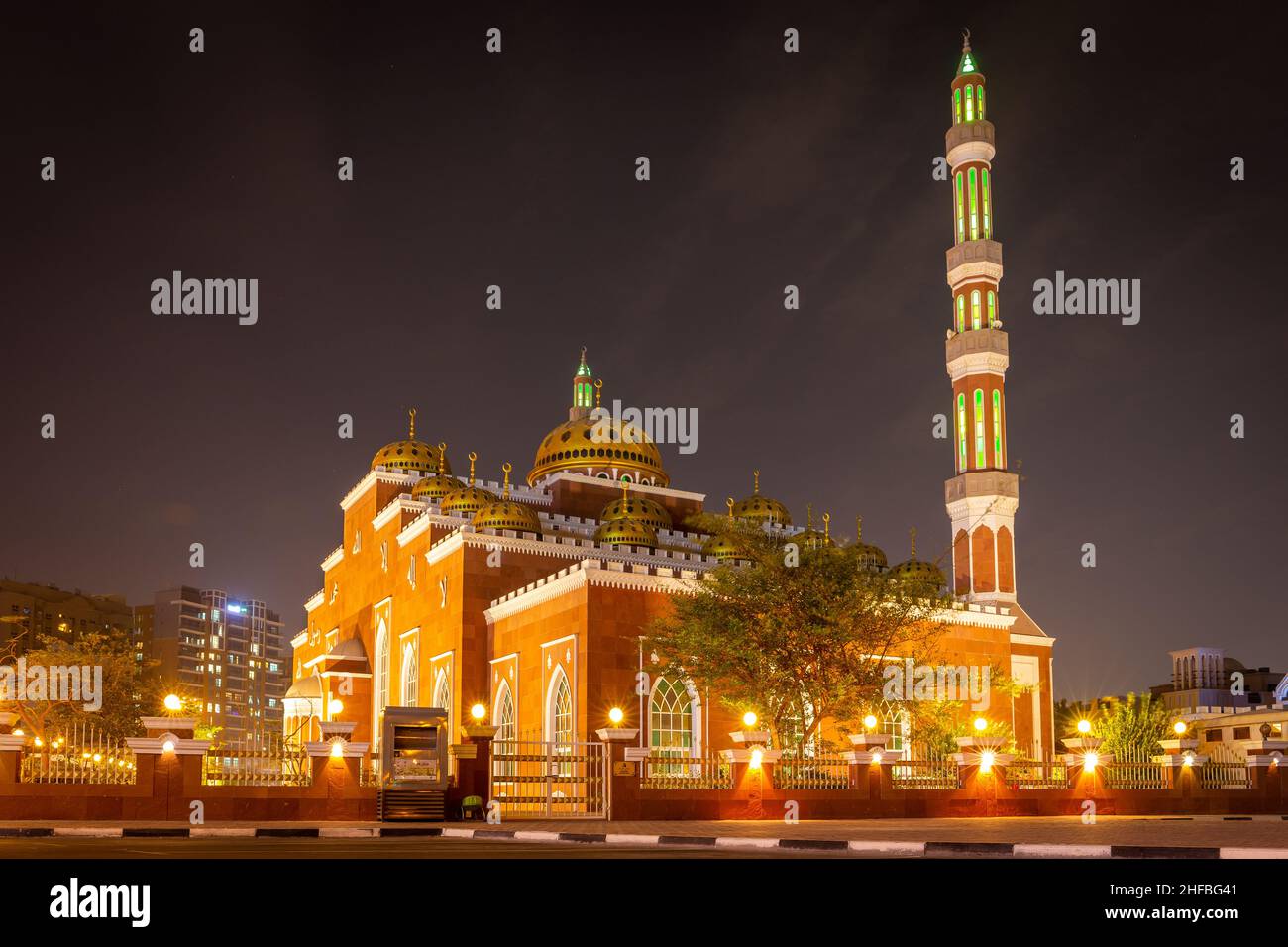 Dubai, UAE, 24.09.21. Al Salam Mosque (Masjid) in Al Barsha, Dubai, mosque with red facade and golden ornaments at night with green illuminations. Stock Photo