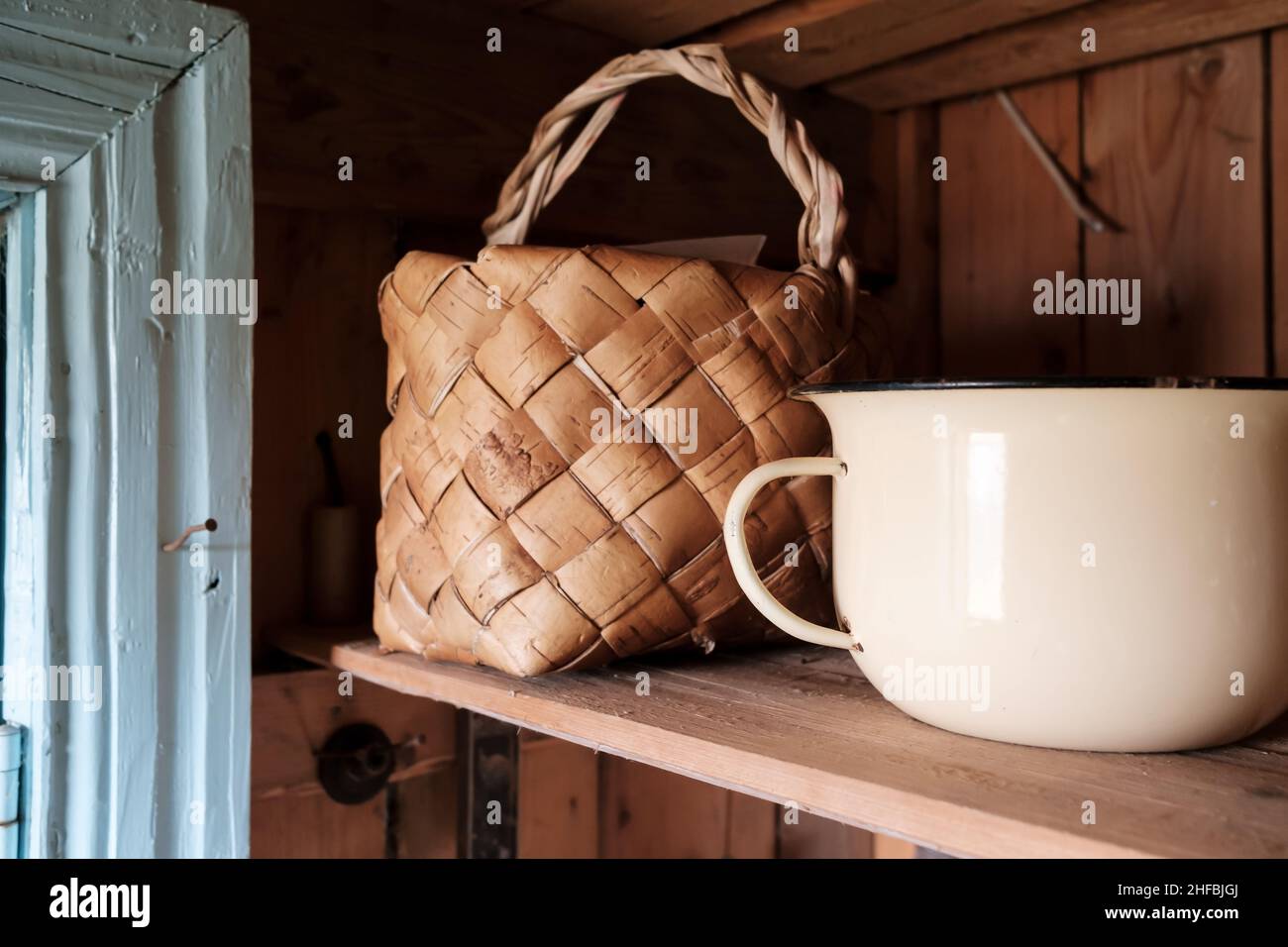 Homemade birch bark basket for picking berries and mushrooms stands on a wooden shelf, next to a