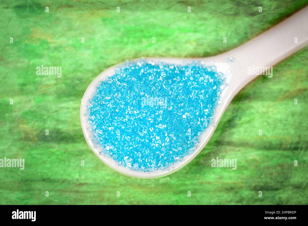 Confectionary turquoise sugar in a white spoon Stock Photo