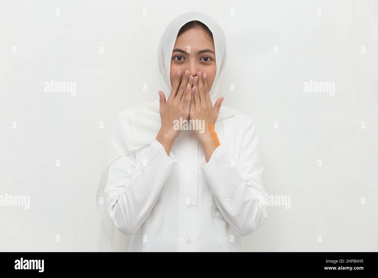 Young asian woman wearing hijab shocked covering mouth with hands for mistake. Secret concept. Stock Photo