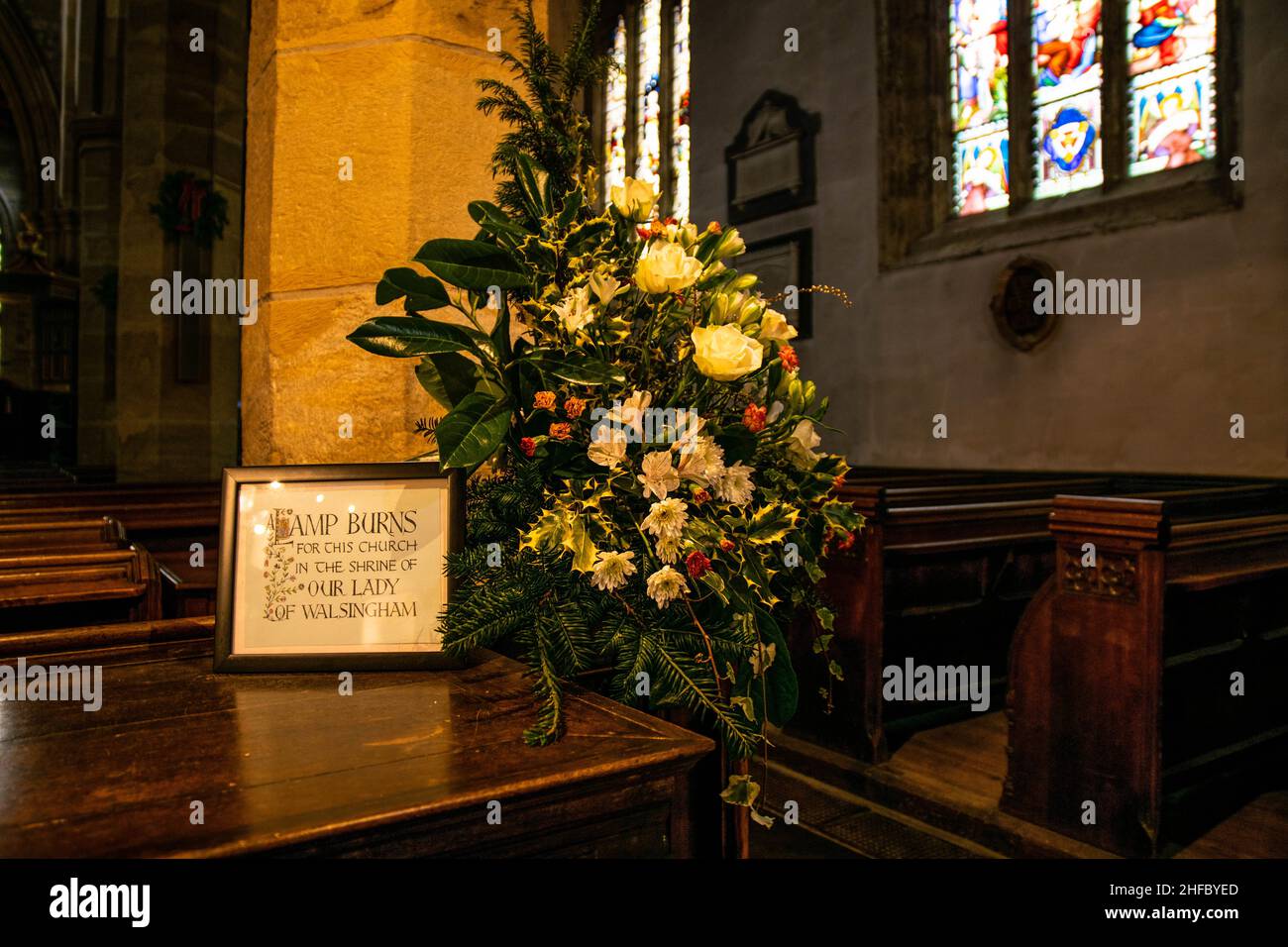 Lancaster, Britain - 4th January 2020: Inside interior of Lancaster Cathedral. Blossoming flowers in a beautiful floral arrangement with stained glass Stock Photo
