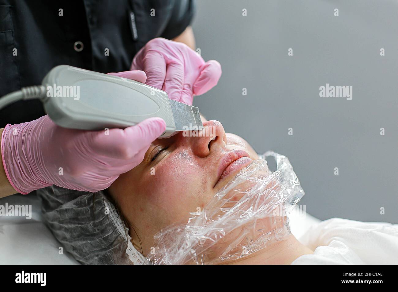 Cosmetologist girl does ultrasonic cleaning of the face Stock Photo