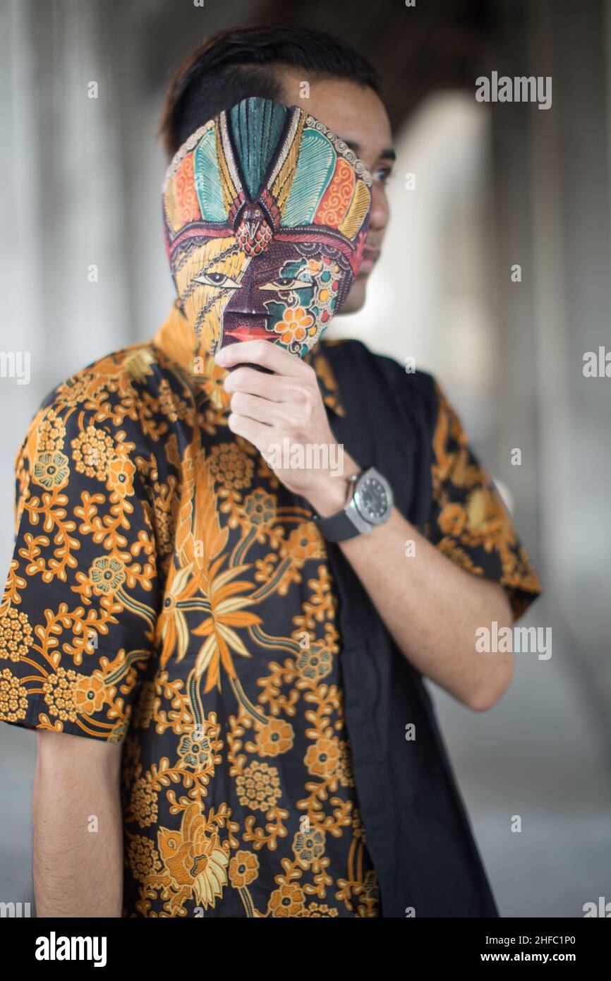 A young male model dressed in traditional Indonesian Batik and a Javanese mask at the Long Museum, West Bund, Shanghai, China Stock Photo