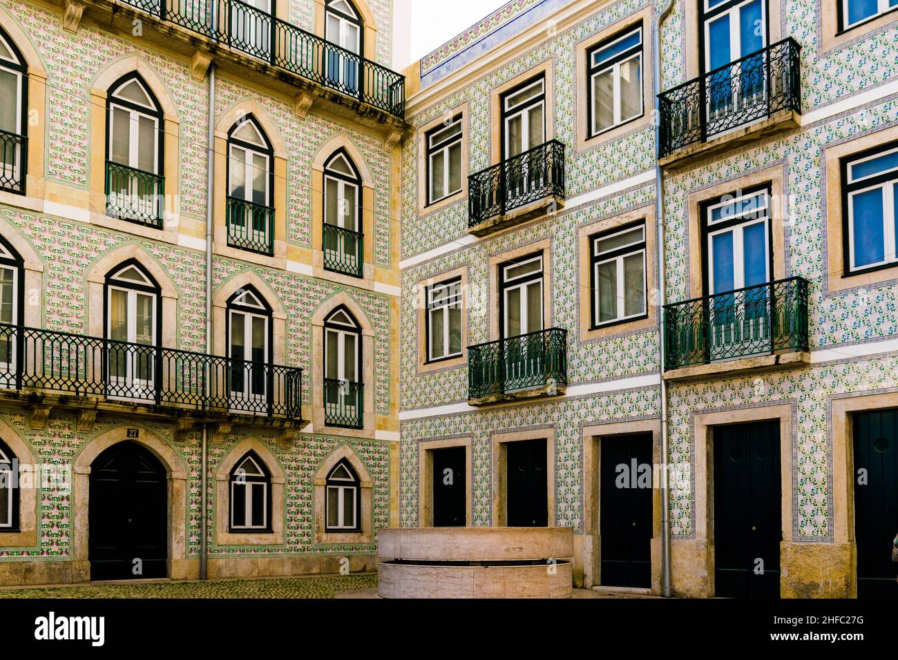 Apartment building within a court yard with green balconies, decorated with lots of fine painted colourful azulejos ceramic tiles in city Lisbon Stock Photo