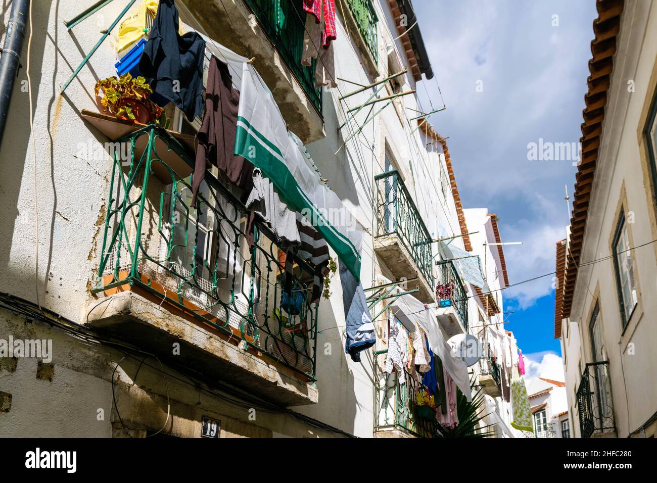 Lots of clothes hanging from balconies in the narrow streets of Alfama district, Lisbon, Portugal. Typical traditional simple way of life in the old Stock Photo