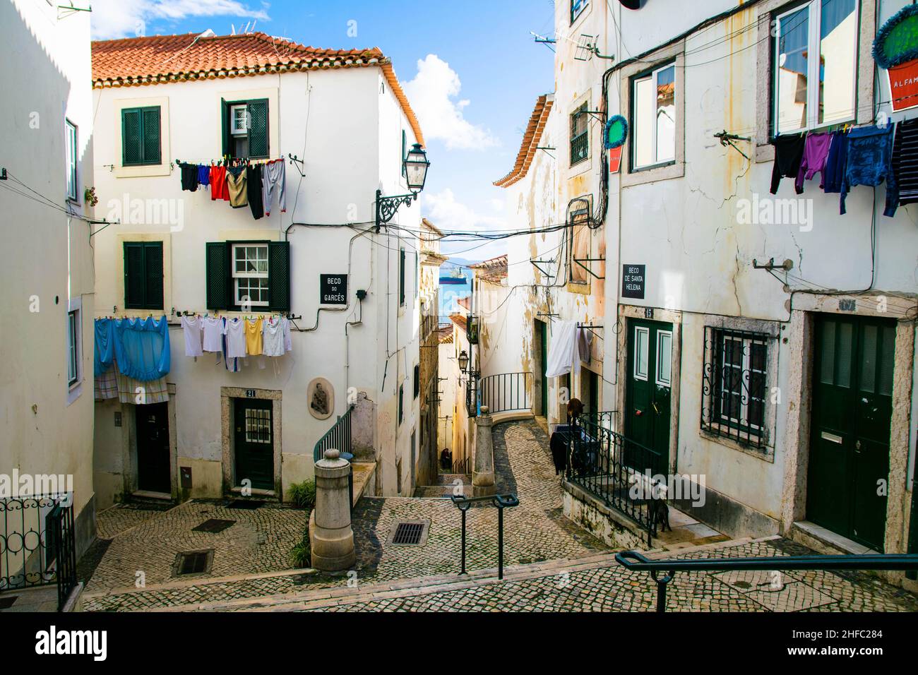 Lots of clothes hanging from balconies in the narrow streets of Alfama district, Lisbon, Portugal. Typical traditional simple way of life in the old Stock Photo