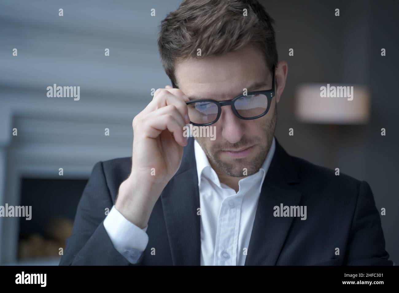 Concentrated handsome austrian businessman dressed in suit adjusting glasses while working in office Stock Photo