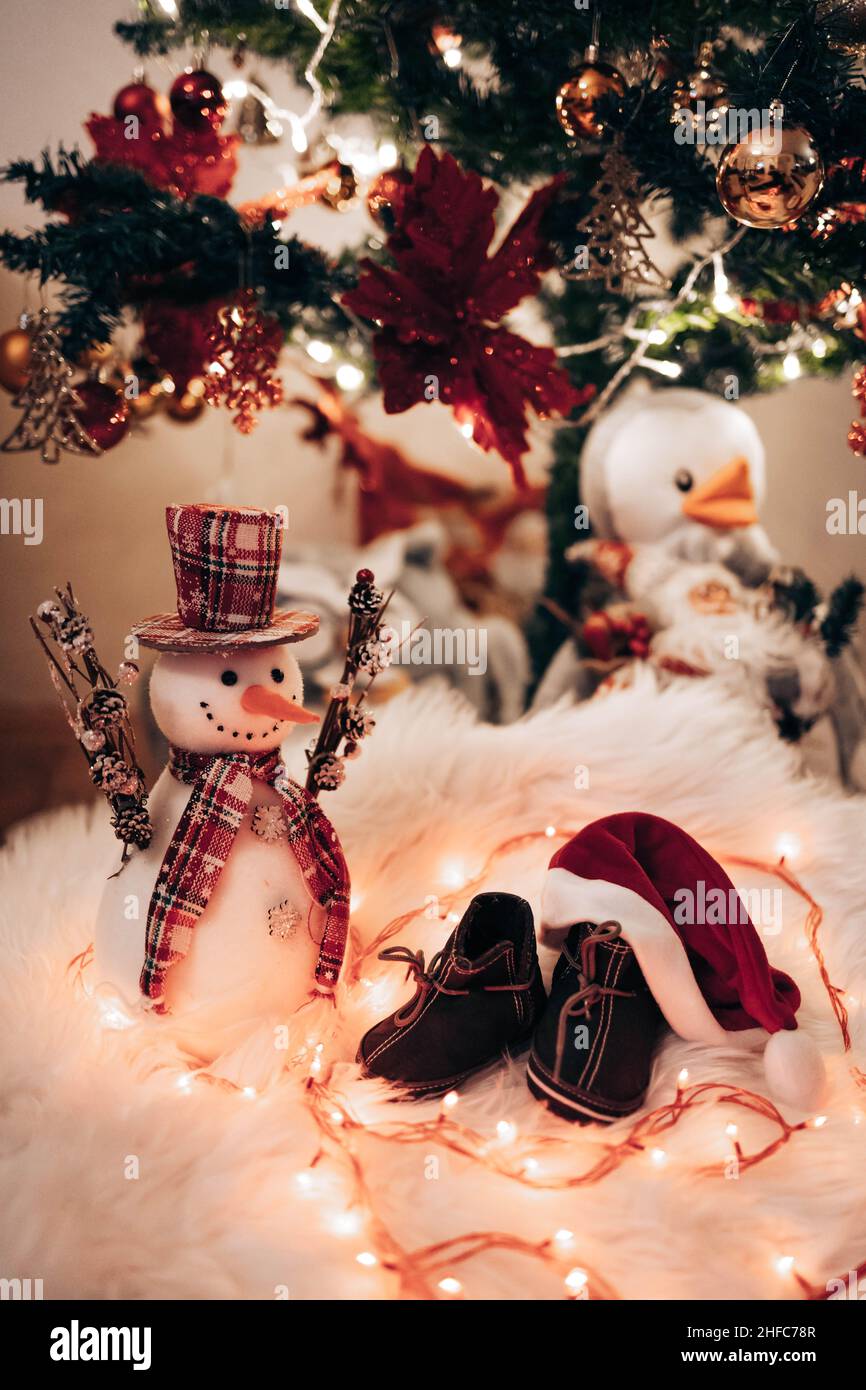 Baby shoes under a Christmas tree with snowman toy Stock Photo