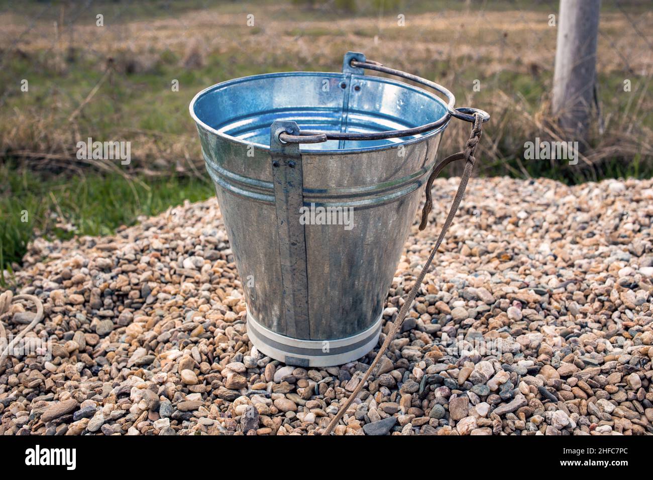 Metal water bucket with handle and rope outdoors Stock Photo