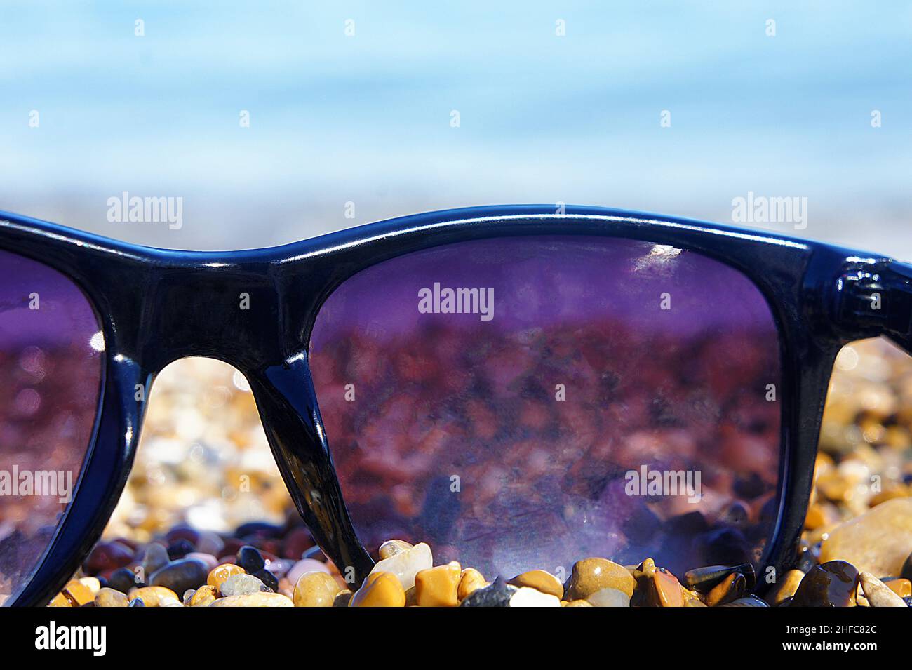 Plastic sunglasses against the background of sea stones. Stock Photo