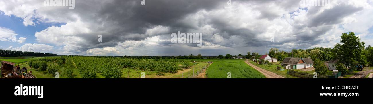 Panorama of sky with clouds and green field with garden Stock Photo - Alamy