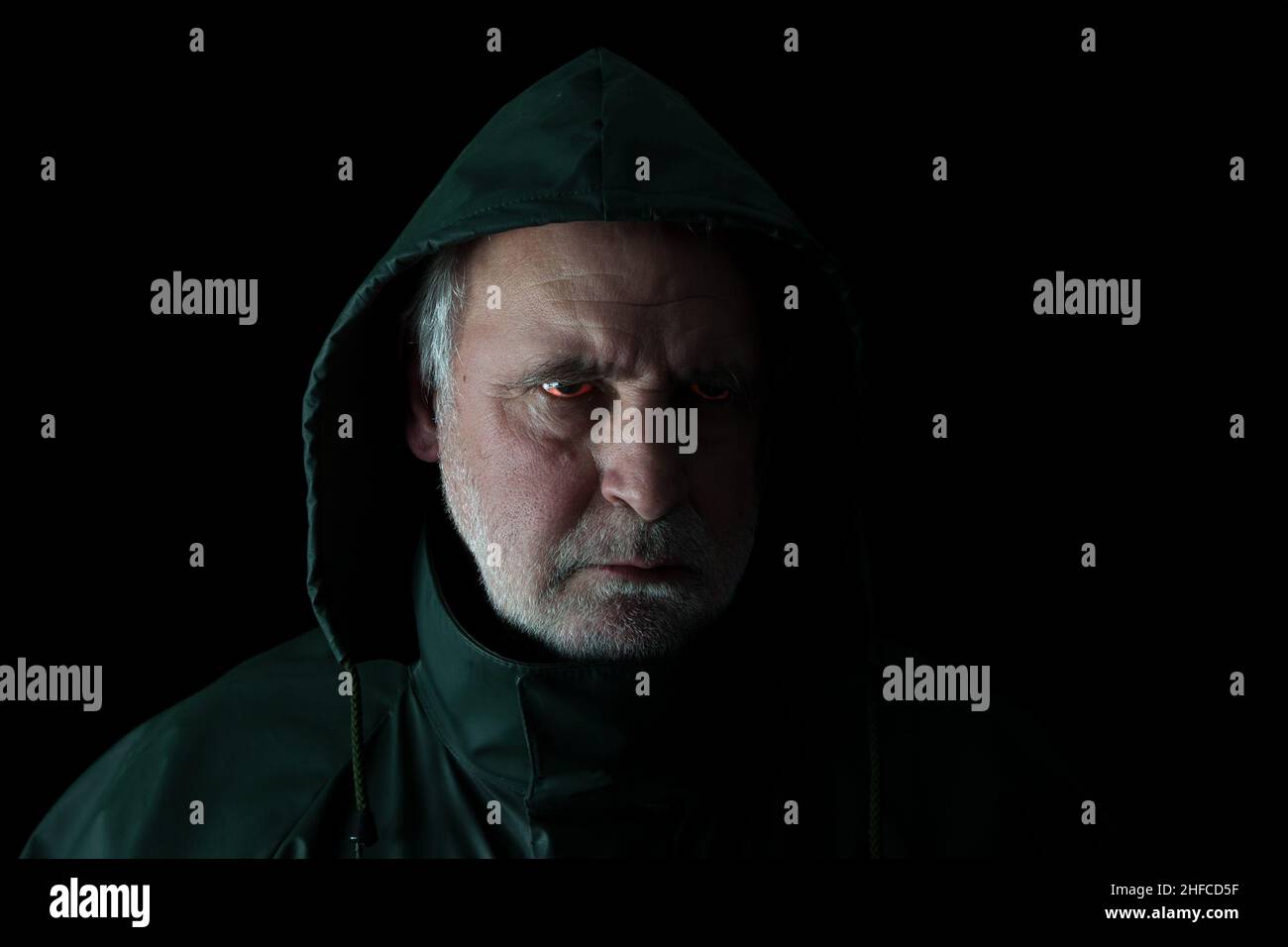 A bad man. Hooded man looks angry with bloodshot eyes. Stock Photo
