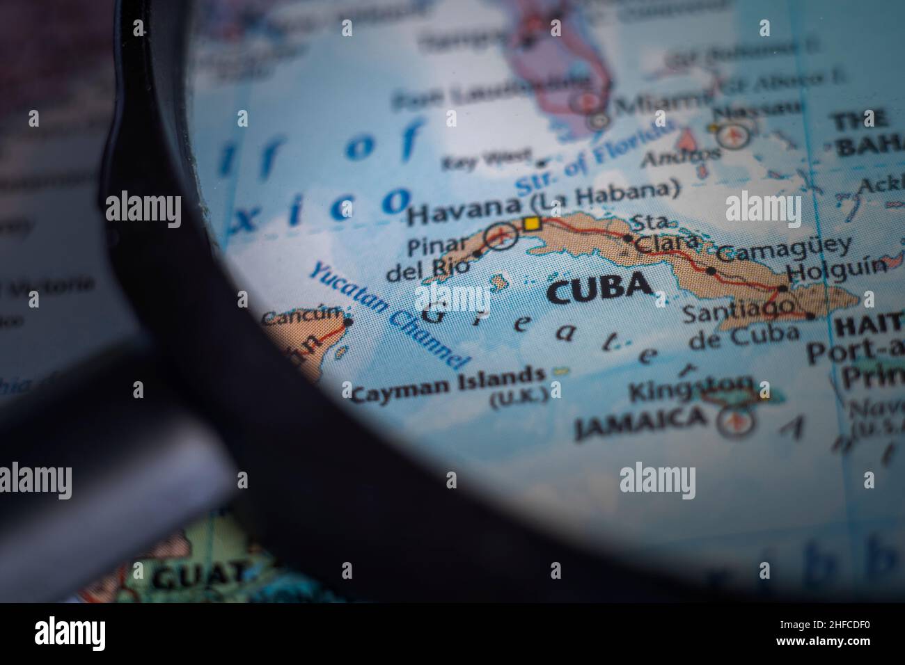 Cuba on a world map through magnifying glass. Cuban travel destination planning pinned Stock Photo