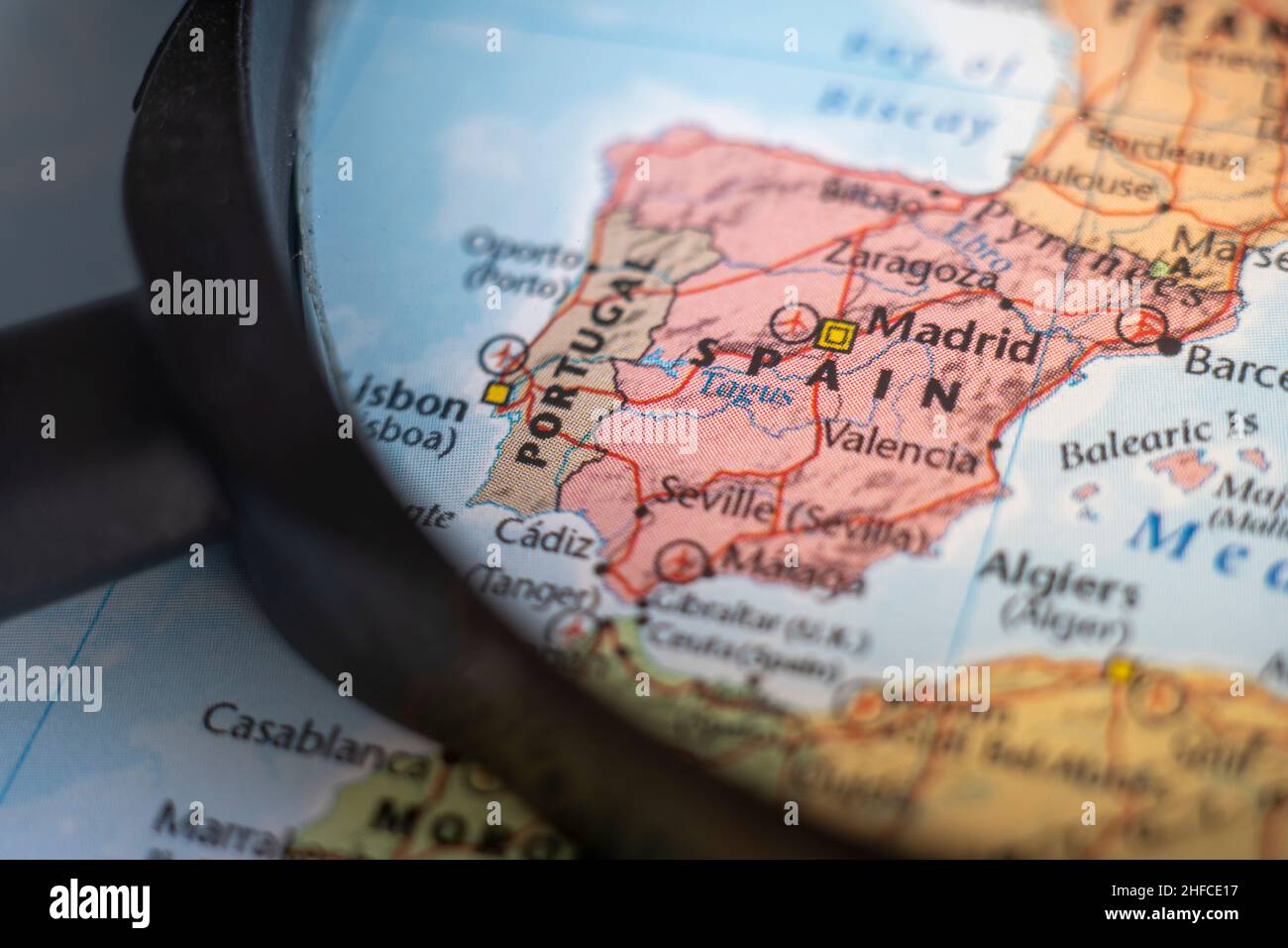 Portugal and Spain, Iberian Peninsulaoo n a world map through magnifying glass. Portugal and spain travel destination planning pinned Stock Photo