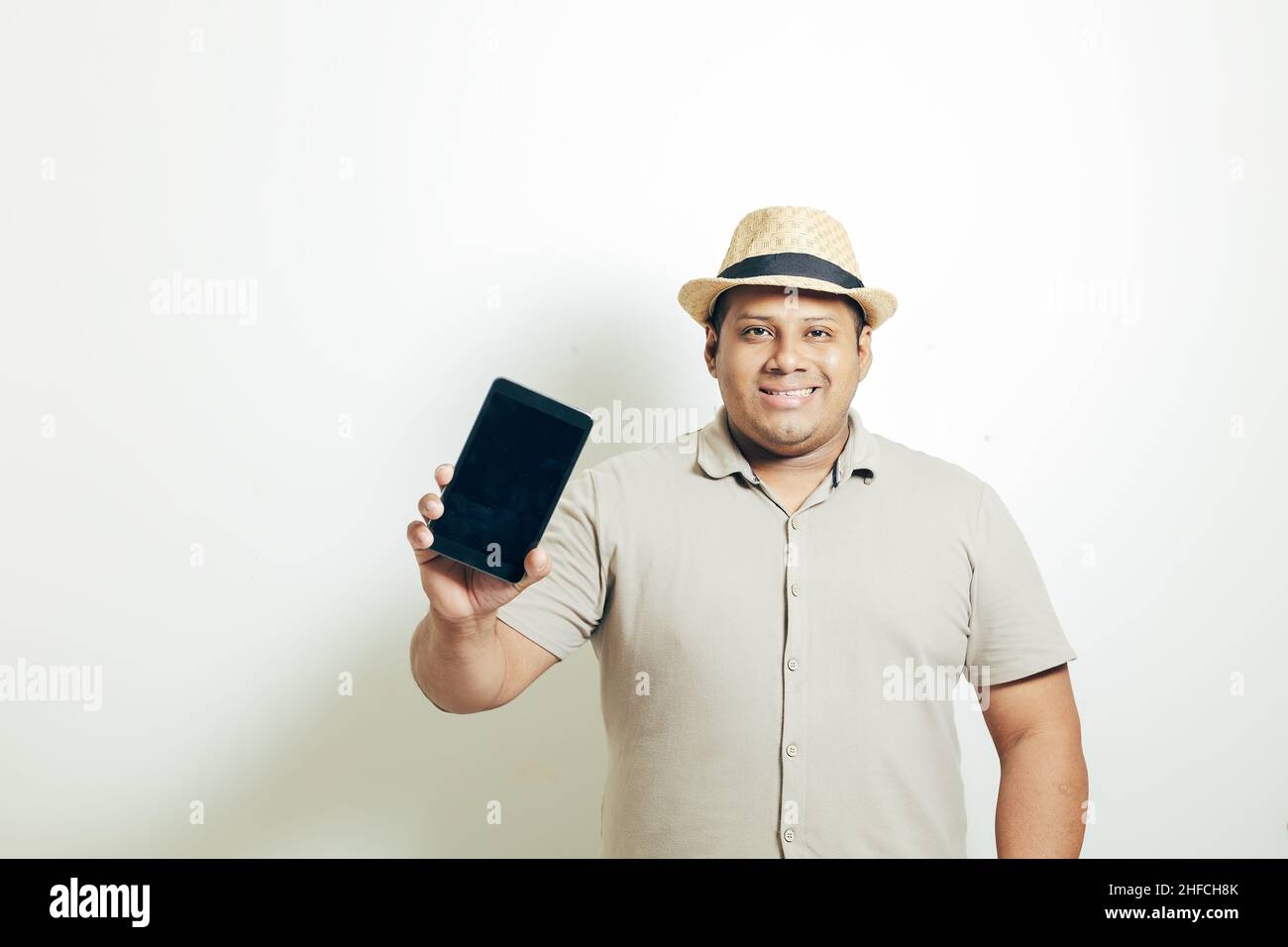 hispanic man with hat showing the mobile very happy, on white background Stock Photo
