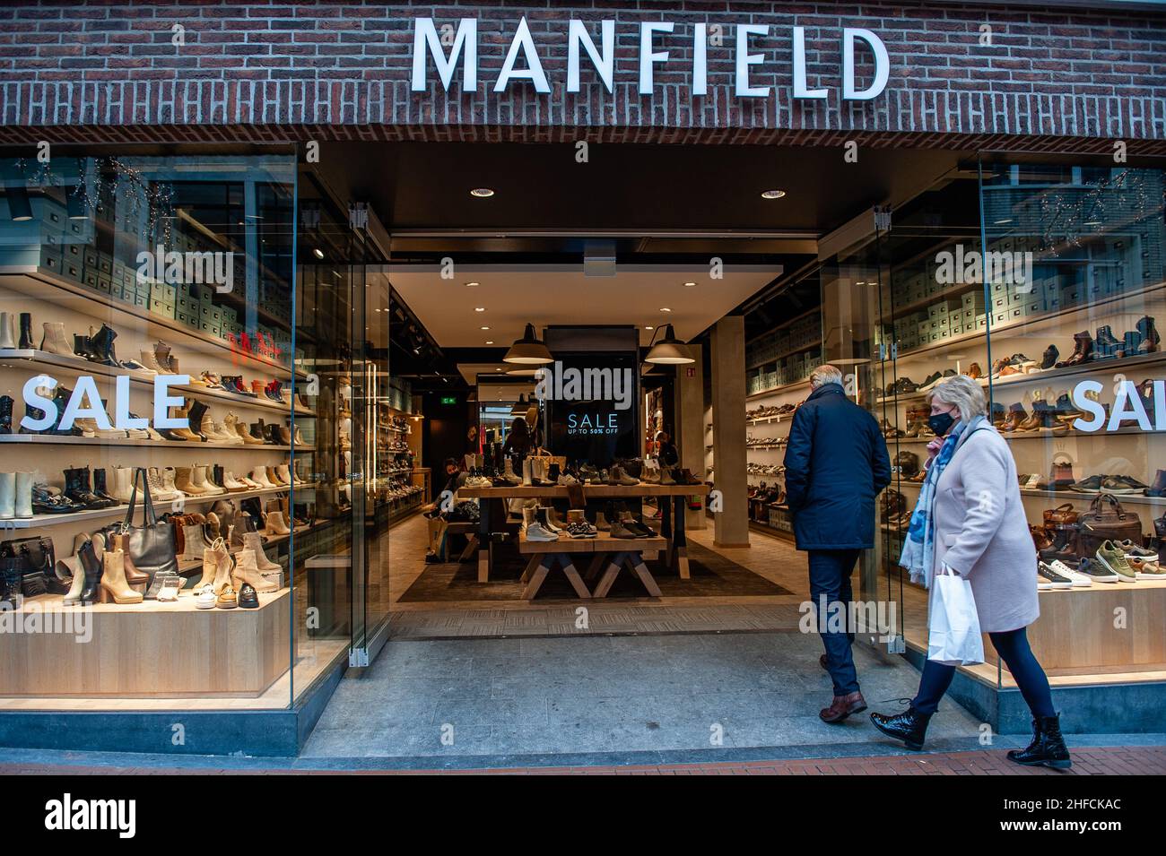 An elderly couple seen walking inside of Manfield shoes store.Last