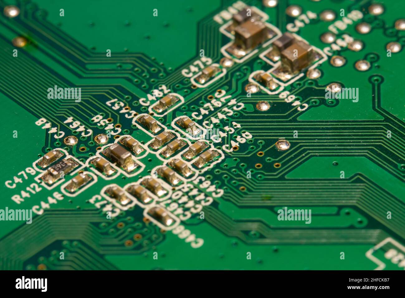 Many small electronic components soldered on green printed circuit board (PCB). Stock Photo
